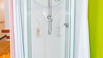 A shower enclosure with a glass door, a handheld showerhead, and a bottle of soap.