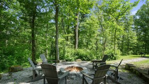 Un foyer entouré de fauteuils Adirondack, situé dans une zone boisée.