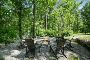 A fire pit surrounded by Adirondack chairs in a forested area. - Rising Ridge Lodge | Hocking Hills, 12 Acres (Logan)
