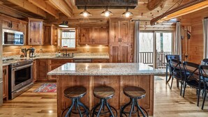 L’intérieur d’un chalet en bois comprend une cuisine dotée d’un comptoir en granit, d’appareils électroménagers en acier inoxydable et d’un coin bar avec des tabourets.