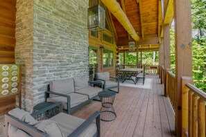 A wooden deck with outdoor seating, stone walls, and large windows.