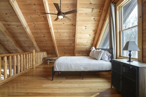 A bedroom with a bed, a ceiling fan, a window, and a nightstand.