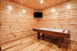 A wooden room with a pool table and a mounted television.