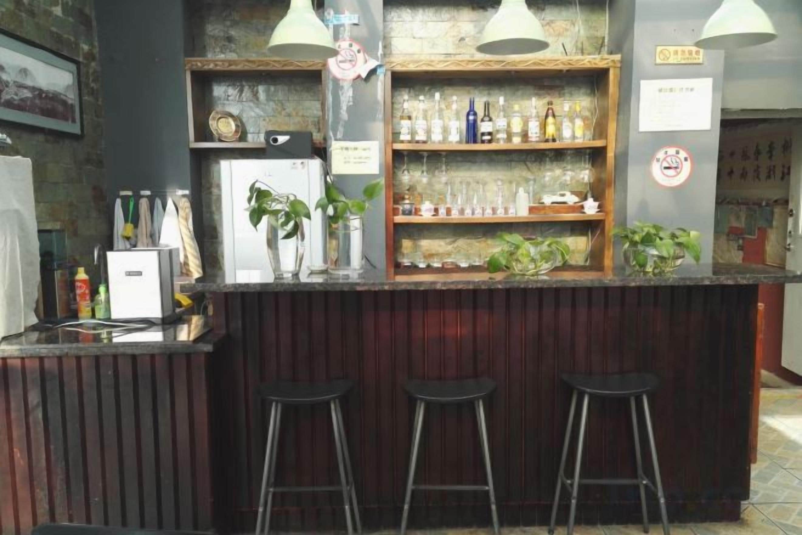 A bar area with stools, shelves with bottles, and a refrigerator.
