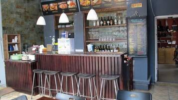 A bar area with stools, a counter, and a menu board.