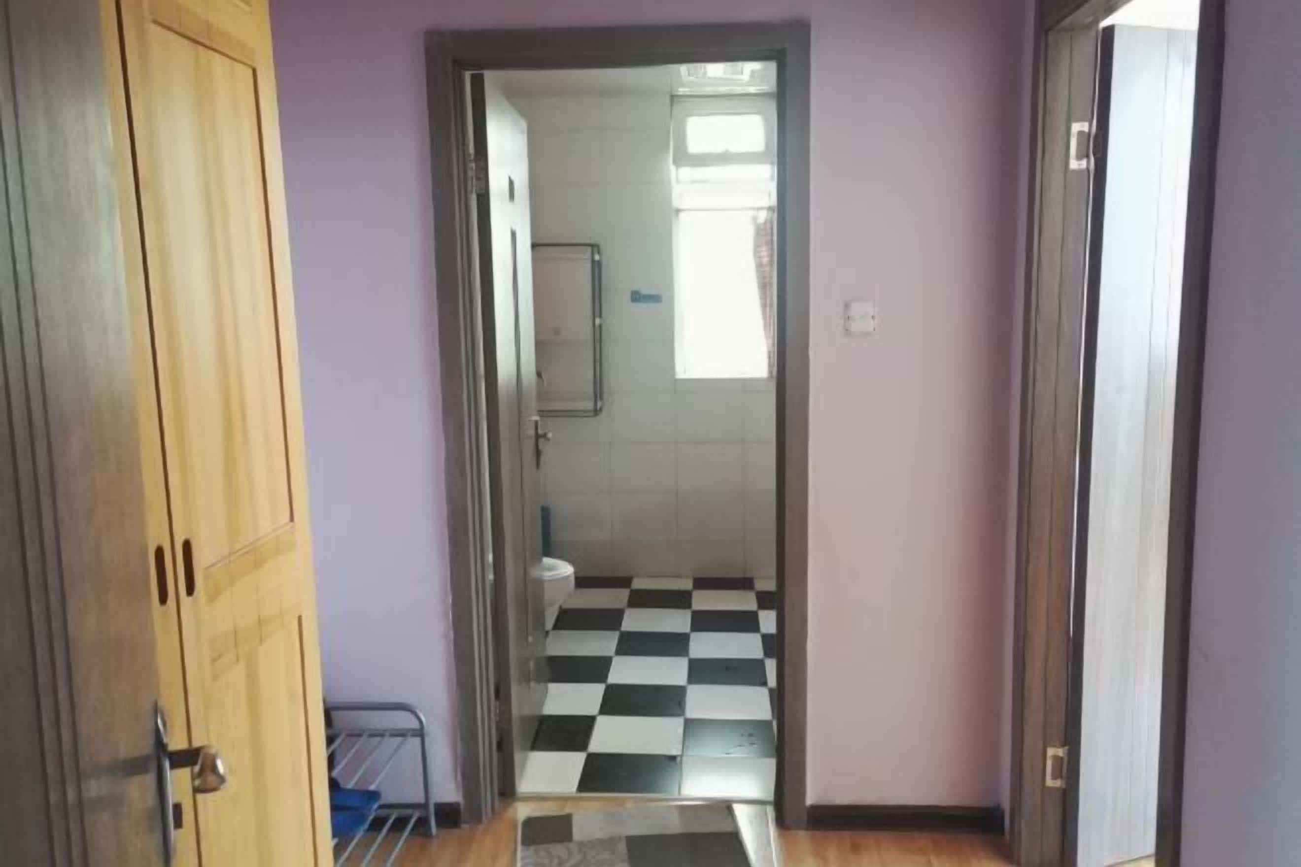 Pasillo que lleva a un baño con piso a cuadros, inodoro y espejo.