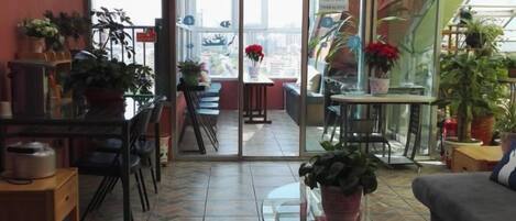 Une pièce comprenant un coin repas, un canapé et donnant sur l’extérieur grâce à une porte vitrée.