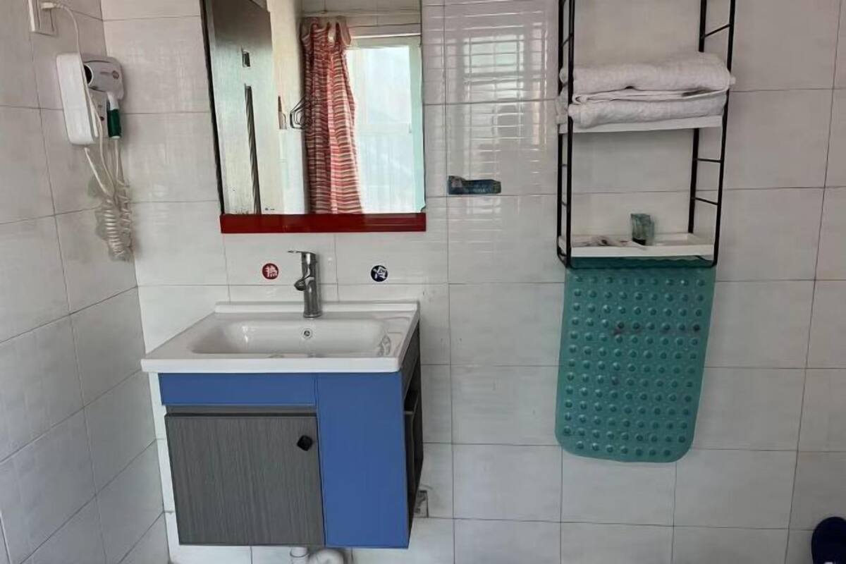 A bathroom with a sink, mirror, towel rack, and a green bath mat.