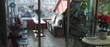 A balcony with seating, a table, and potted plants.