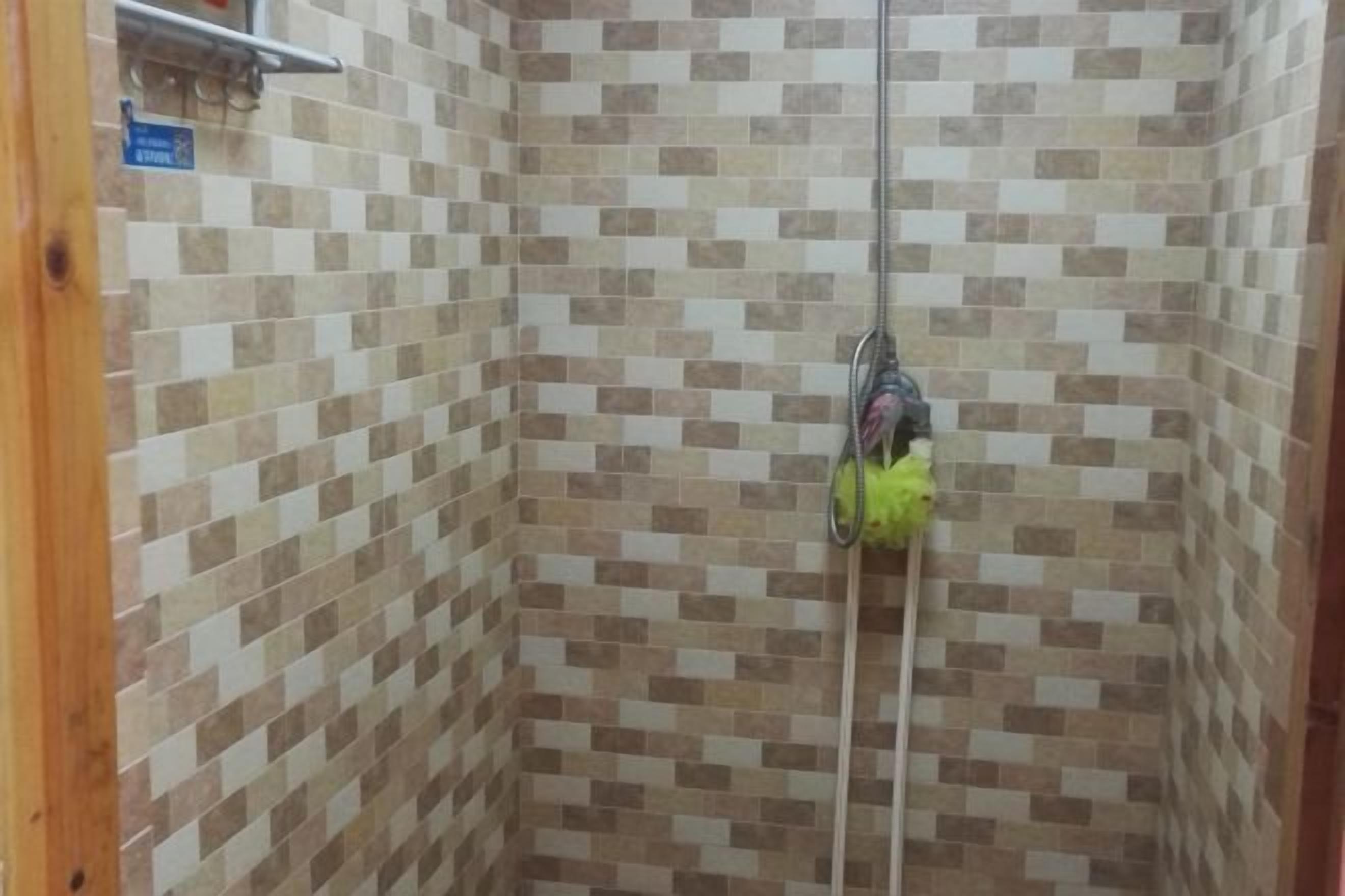 A shower area with tiled walls and a showerhead.