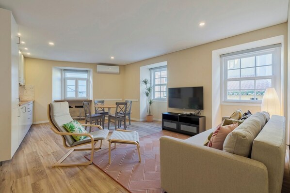 Relax in this stylish living room with a large flat-screen TV, comfortable sofa, and dining area.
