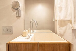 Une salle de bain avec un meuble-lavabo en bois, un évier, un miroir et une serviette accrochée au mur.