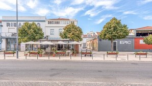 Une vue d’une rue avec un café appelé « PEREZ », qui dispose d’une terrasse et de plantes en pot.