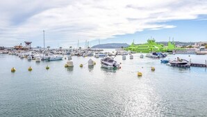 Un port de plaisance où sont amarrés de nombreux bateaux, un bâtiment vert doté d’un toit en forme de flèche et un ciel dégagé.