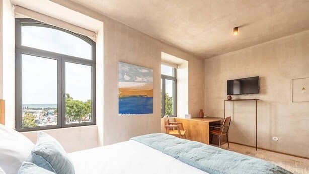 Une chambre avec un grand lit, un bureau et une télévision.