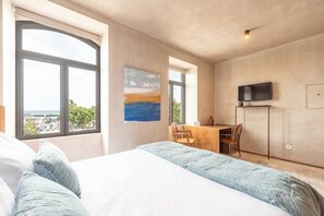 Une chambre avec un grand lit, un bureau et une télévision.