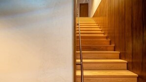 Un escalier en bois avec une rampe métallique, menant à une porte située en haut.