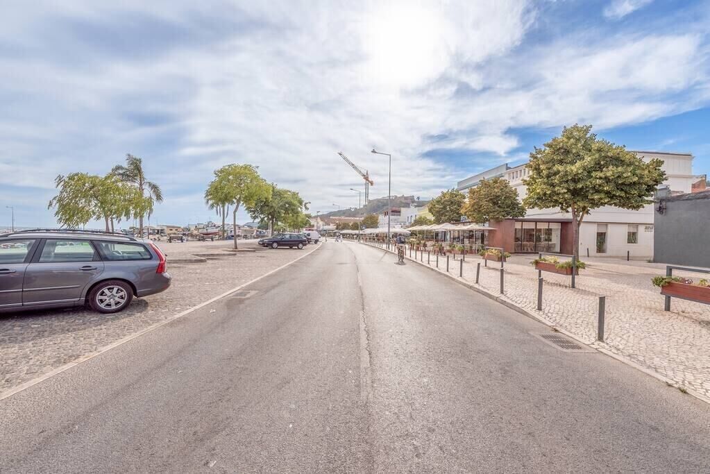 Eine Straße mit parkenden Autos, Bäumen und Gebäuden.