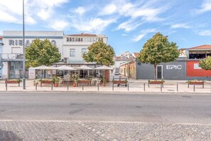 Straatbeeld met een café genaamd 'PEREZ', met terras en plantenpotten.