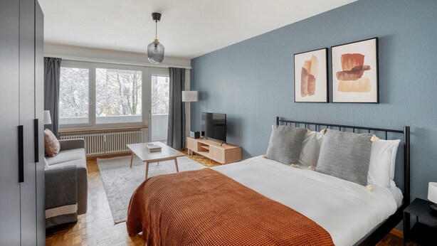Une chambre à coucher moderne avec un lit, des tables de chevet, un téléviseur et des œuvres d’art accrochées au mur.