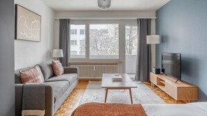 Un salon moderne avec un canapé, une table basse, un téléviseur et une fenêtre avec des rideaux.