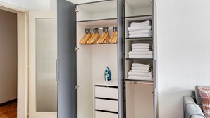 Un dressing accessible sans porte, où l’on peut voir des serviettes soigneusement pliées et des cintres en bois.