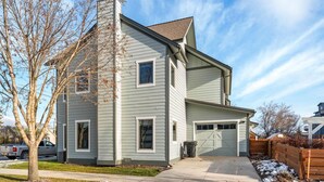 A two-story house with a garage, a chimney, and a tree in the yard. - The Dancing Bears Den (Whitefish)