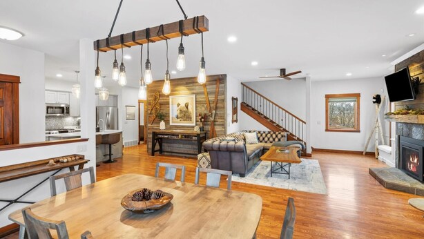 A spacious living area with a wooden dining table, a sofa, and a fireplace. - The Dancing Bears Den (Whitefish)