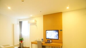 A hotel room with a desk, a chair, a television, a potted plant, a radiator, and a window with curtains. - Greentree Inn Beijing Fengtai District Changxindian Express Hotel (Beijing)