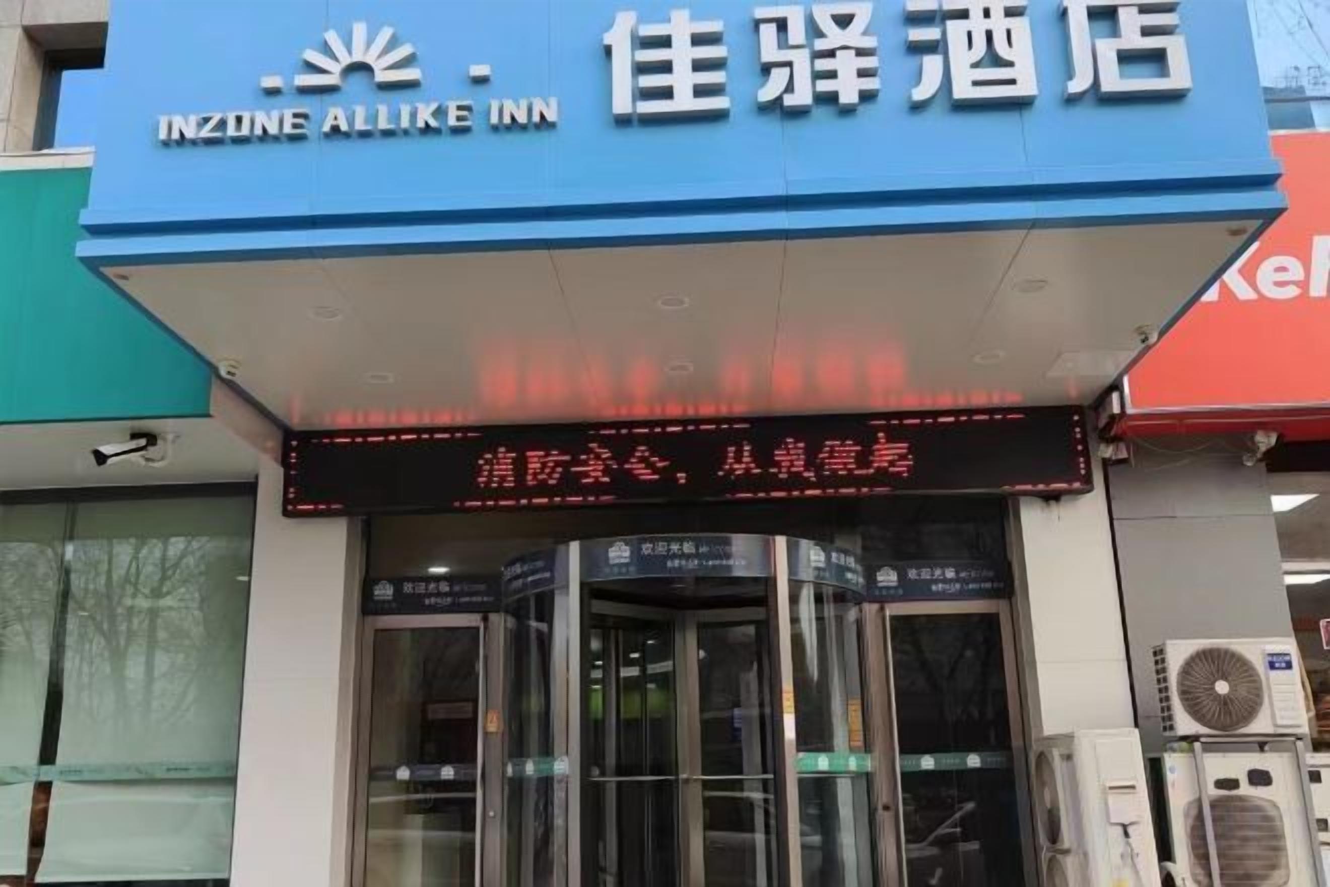 An INZONE ALLIKE INN hotel entrance with a digital display above the doors.