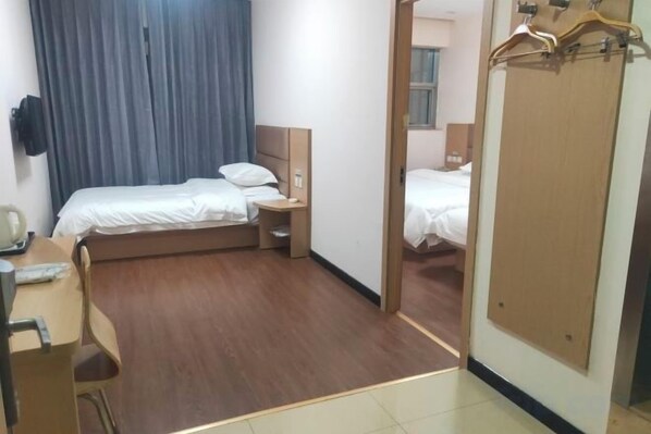 A hotel room with a bed, bedside table, chair, and a mirror.