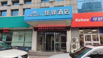 A hotel with a blue sign, a red sign, and a glass facade.