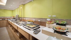 Un buffet avec différents postes de service proposant une variété de plats, notamment des plateaux de nourriture et un bar à salades.