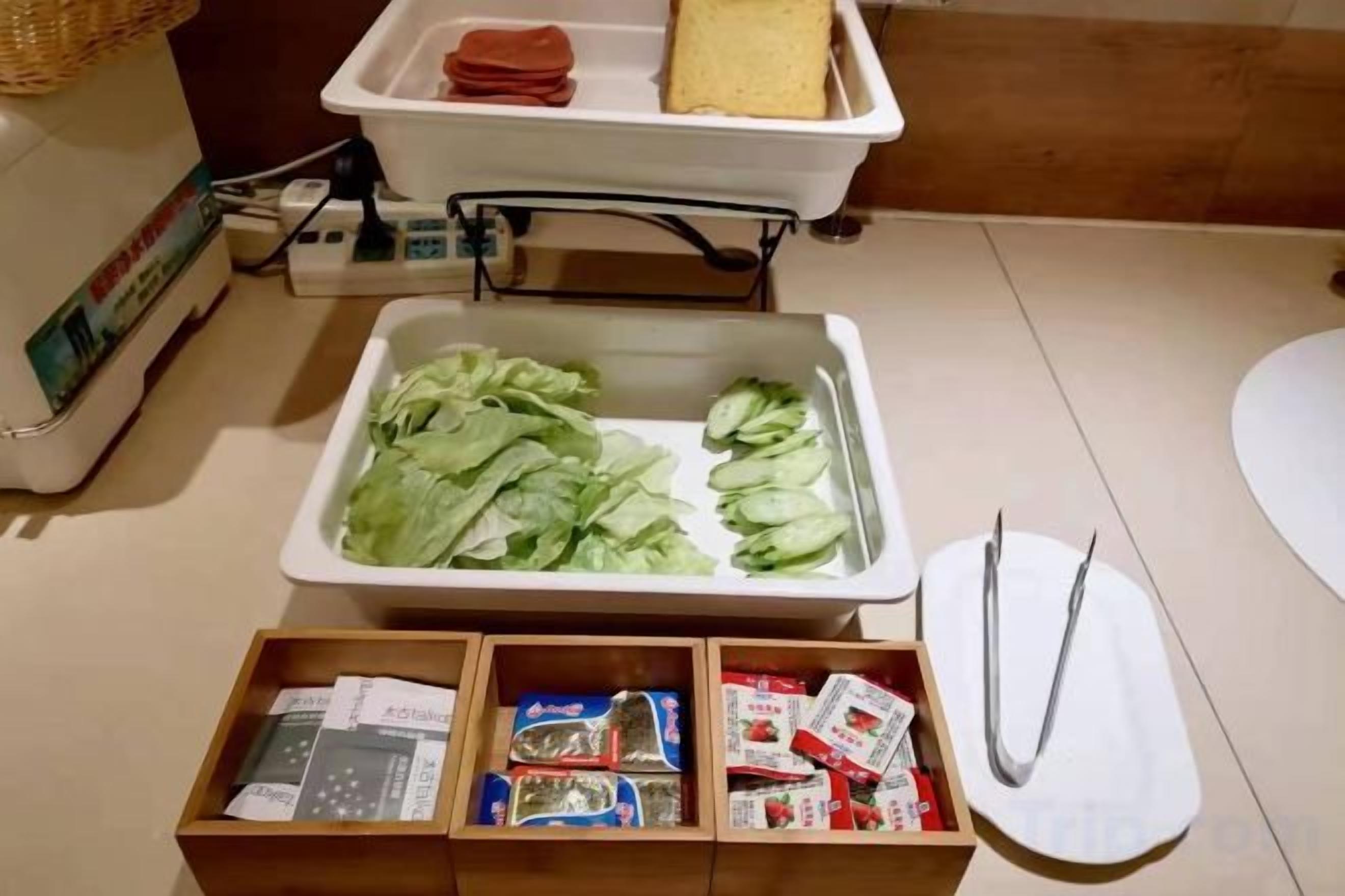 A kitchen area with a sink, a tray of lettuce, and a wooden box containing condiments.