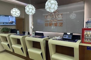 Zona de recepción con mostrador, sillas, pantalla digital y un cartel que dice 'GRACE INN'.