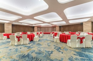 Un salón de conferencias con mesas redondas, sillas blancas y manteles rojos.