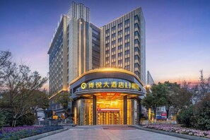 Un hotel con fachada moderna, entrada curva y un letrero que indica que es un hotel.