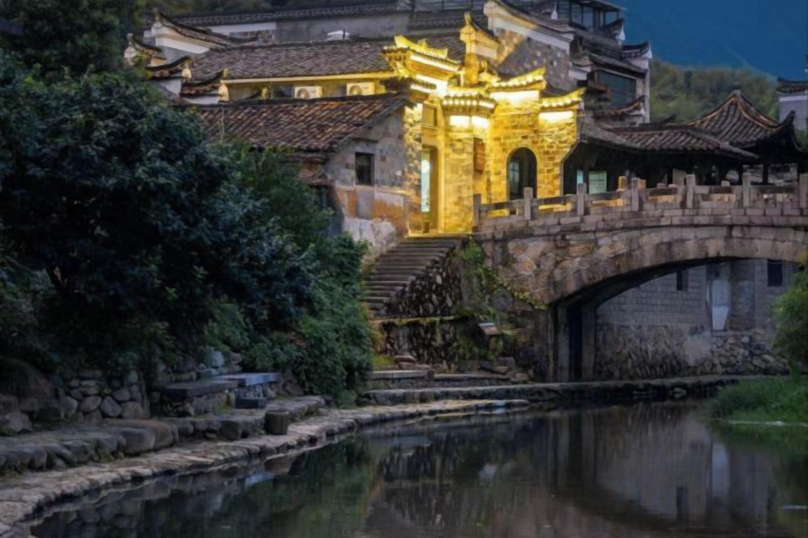 A traditional building with a stone bridge over a canal, reflecting the structure.