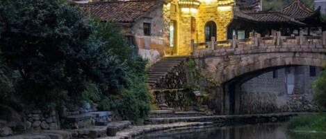A traditional building with a stone bridge over a canal, reflecting the structure.