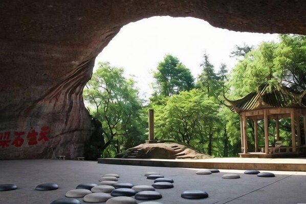 A rock arch with a pavilion and a stone arrangement. - Boyue Hotel (Quzhou)