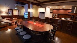 A spacious dining area with a long wooden table, cushioned chairs, and a small plant centerpiece. - Villa Shizen Hakuba (Hakuba)