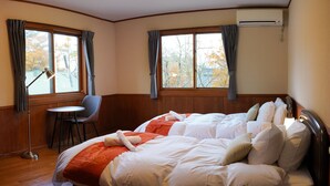 A hotel room with two beds, a chair, a table, and large windows with curtains. - Villa Shizen Hakuba (Hakuba)