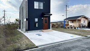 Een modern gebouw met twee verdiepingen, een donkere gevel, een houten deur en een klein portaal met een fiets.