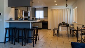 Uma cozinha moderna com uma ilha central, banquetas de bar e um espaço de refeições com mesa e cadeiras.