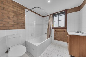 A bathroom with a toilet, bathtub, and sink. - Beach Retreat - Ground Floor 2 Bedroom (Eden)