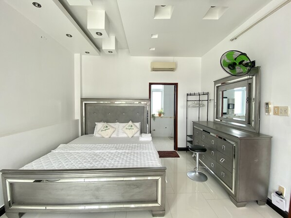 A modern bedroom with a bed, dresser, and vanity.