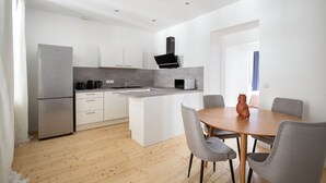 A modern kitchen with a central island, white cabinetry, and a built-in oven.