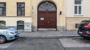 A building with a brown double door, a street sign above the door, and a traffic light to the right.
