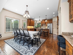 A kitchen with wooden cabinets, a dining table with chairs, and a refrigerator.