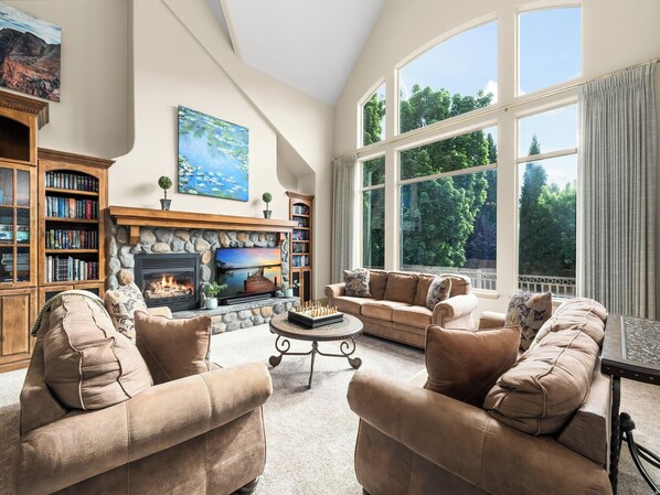 A spacious living room with a fireplace, large windows, and a cozy seating area.